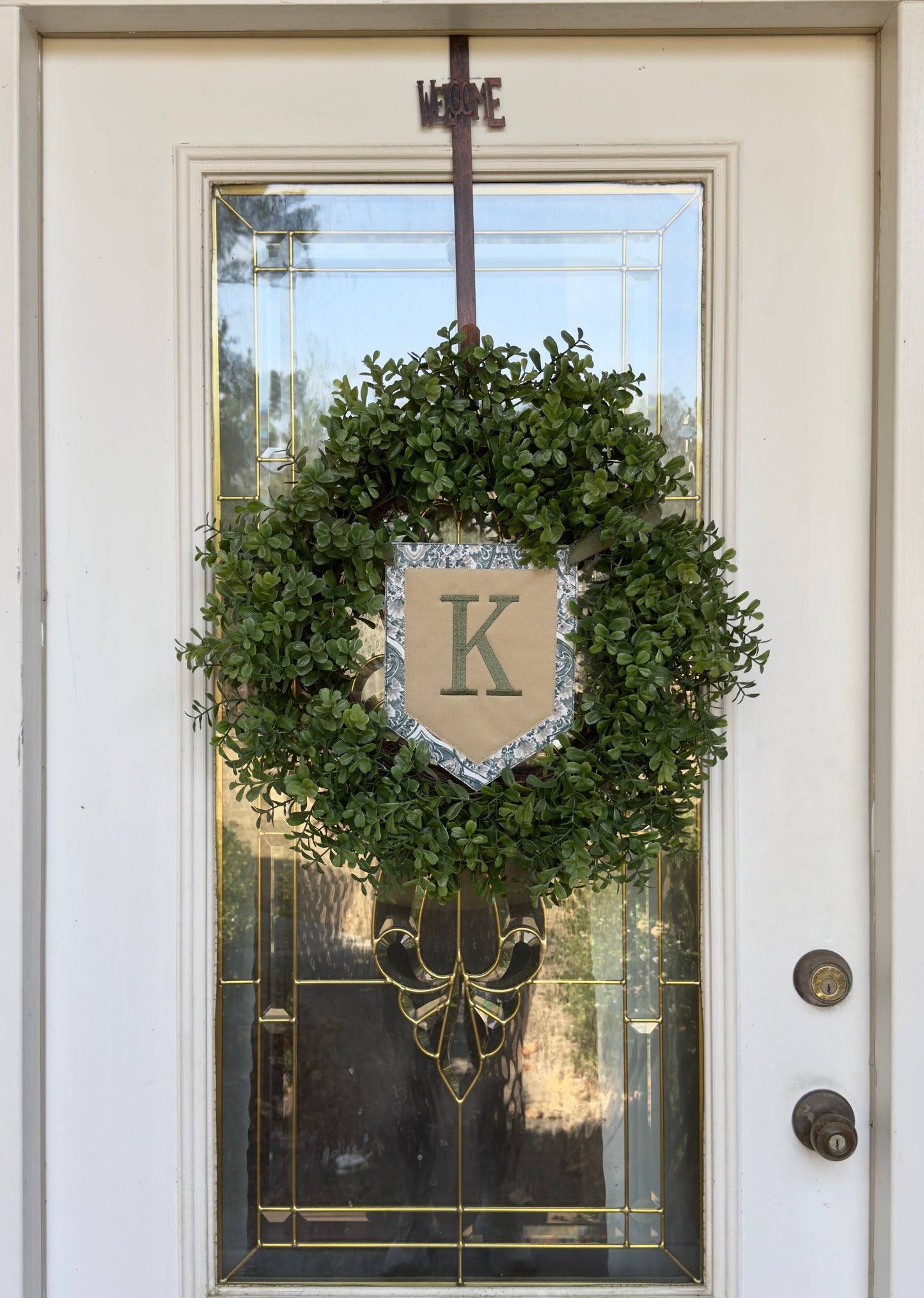 Green wreath with the letter "K" on a decorative 5-sided shape banner