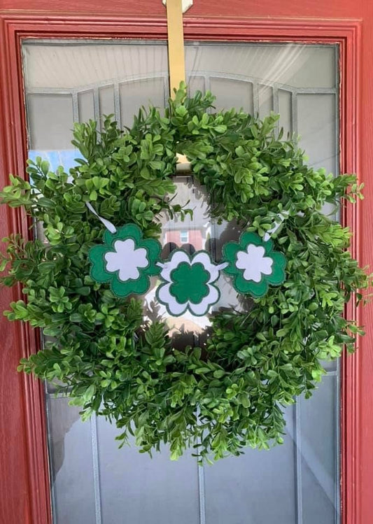 Green wreath with 3 green and white shamrocks attached by ribbon