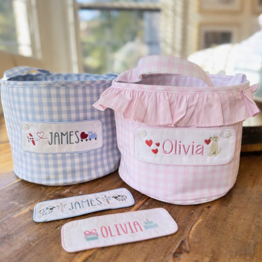 Two fabric baskets, one blue and one pink, with embroidered Valentine's Day images and names 'James' and 'Olivia'