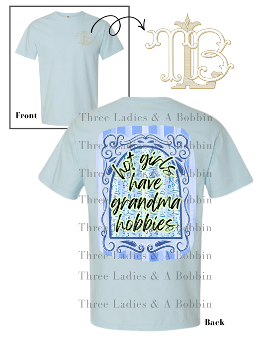 Light blue t-shirt with decorative design and "Hot Girls Have Grandma Hobbies" text